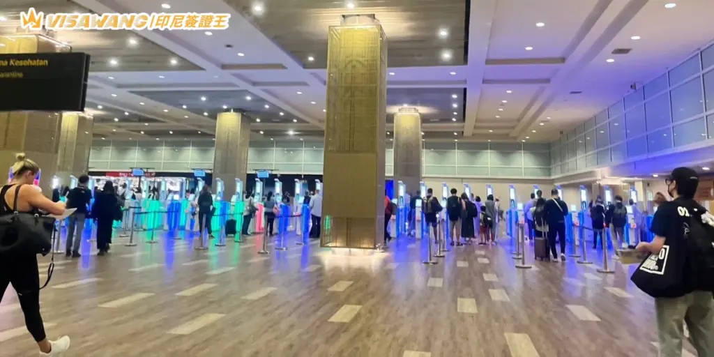 畫面拍攝於峇里島機場入境大廳，可見大量旅客使用電子自動通關閘門（e-Gate）進行入境審查，現場燈光明亮且通道整齊，呈現使用電子簽證快速通關的實際情況。適合用於介紹峇里島 e-Gate 使用方式、印尼電子簽證快速入境流程與機場通關教學相關內容。